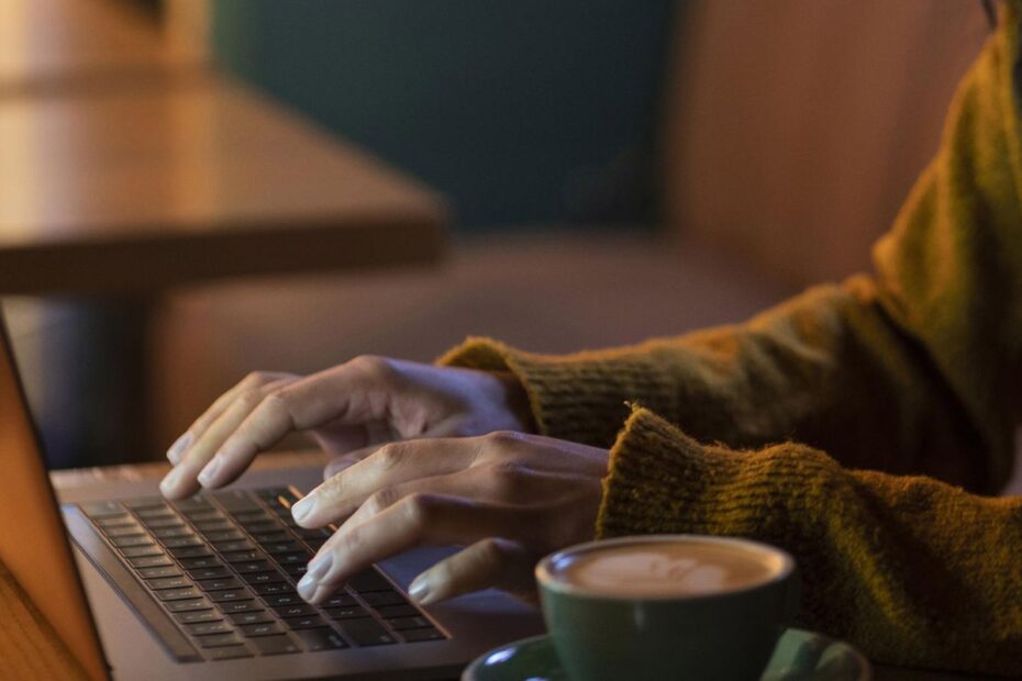 mulher de lado trabalhando em seu laptop em uma cafeteria