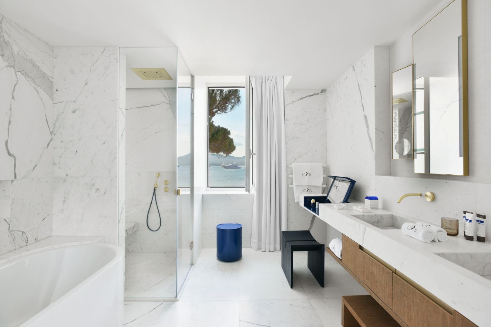 banheiro luxuoso com chão e parede de mármore e vista para o oceano